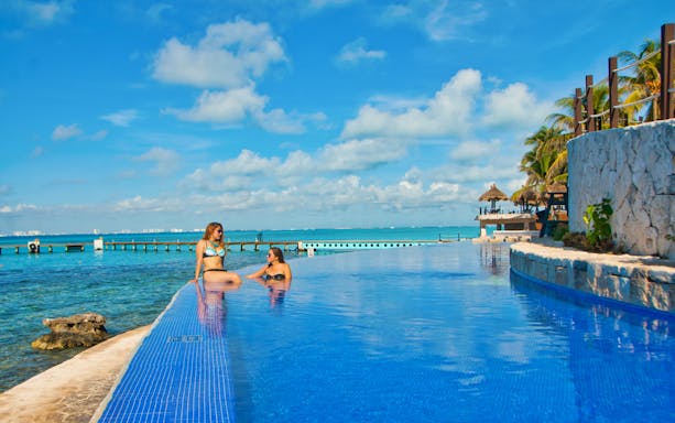 Infinity pool overlooking the ocean at Isla Mujeres with two people relaxing.