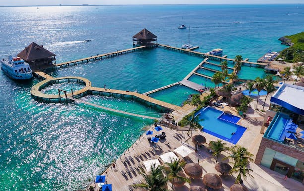 Aerial view of Isla Mujeres dolphin swim area with docks and pools near Royal Garrafón Reef Park.
