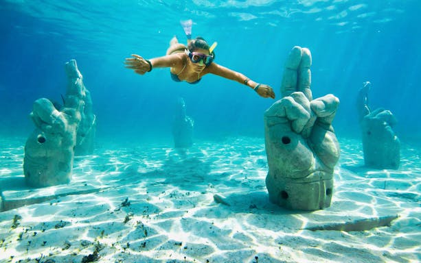 Snorkeler exploring underwater sculptures at Garrafón Reef Natural Park, Isla Mujeres.