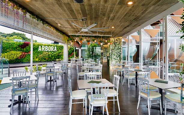 Outdoor dining area at Arbora, Mount Faber, with greenery and seating.