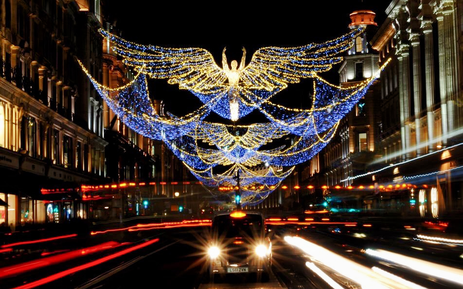 Christmas lights shaped like angels over a busy London street on Christmas Eve.