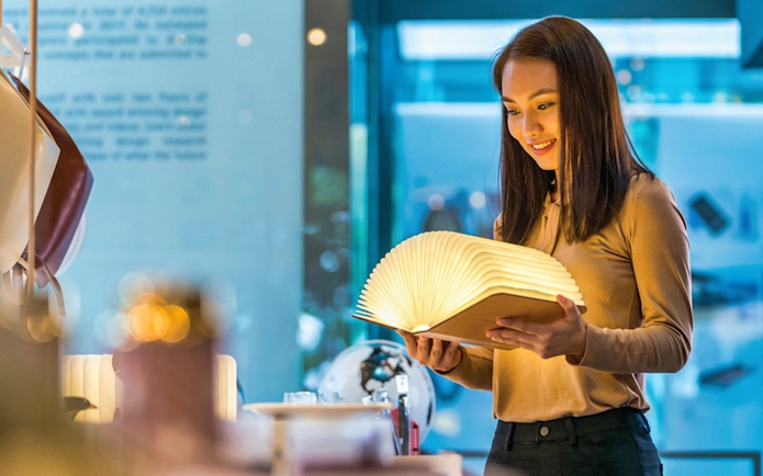 Visitor exploring illuminated book at Red Dot Design Museum, Singapore.