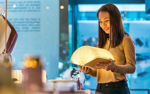 Visitor exploring illuminated book at Red Dot Design Museum, Singapore.