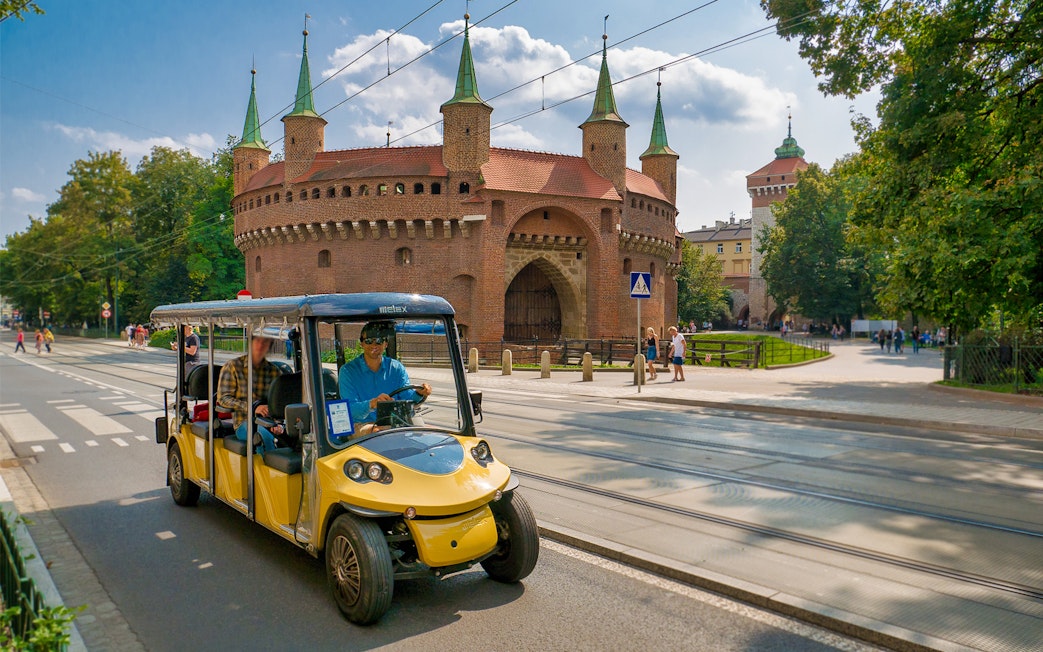 Electric car tour passing Krakow's historic Barbican.