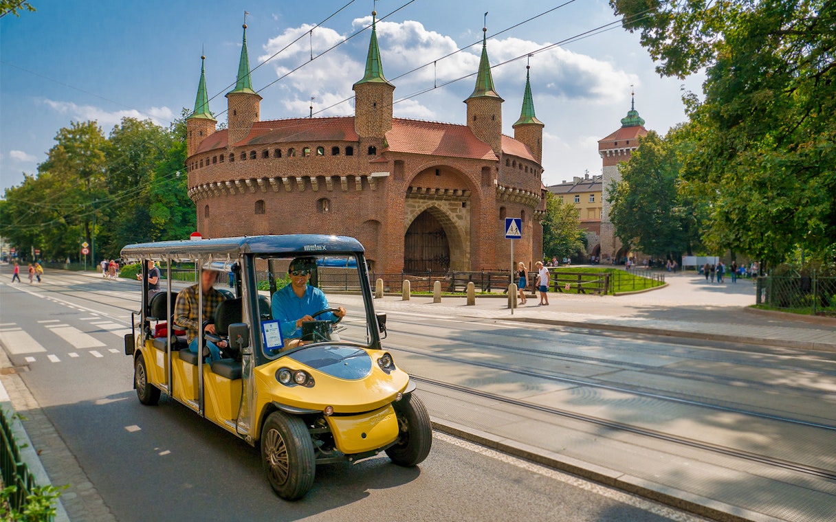 Electric car tour passing Krakow's historic Barbican.
