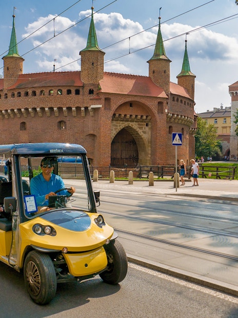 Electric car tour passing Krakow's historic Barbican.