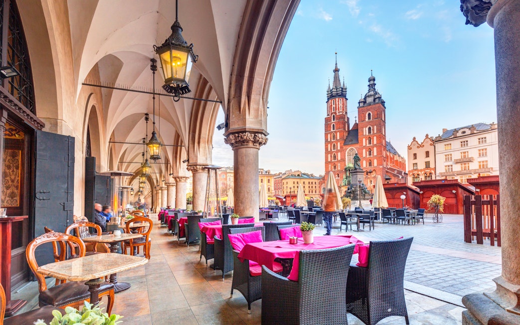 Outdoor café under arches with view of St. Mary's Basilica in Krakow, Poland.