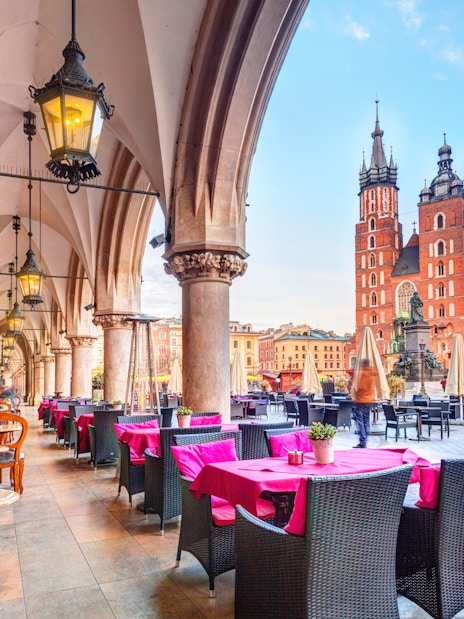 Outdoor café under arches with view of St. Mary's Basilica in Krakow, Poland.