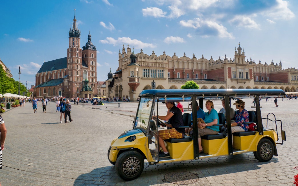 Electric car tour in Krakow's Main Square with St. Mary's Basilica in the background.