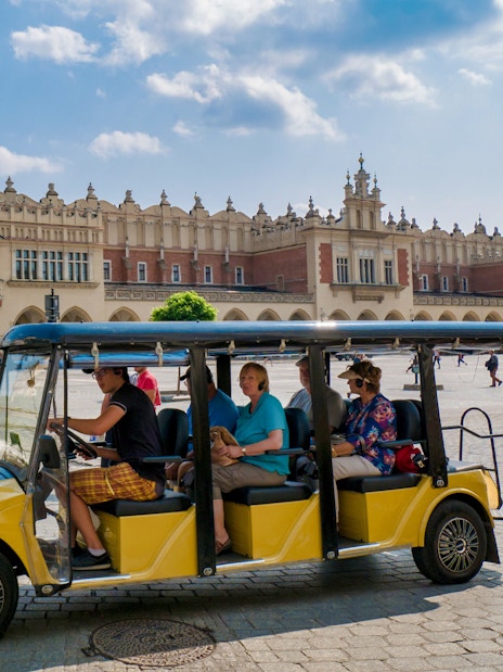 Electric car tour in Krakow's Main Square with St. Mary's Basilica in the background.