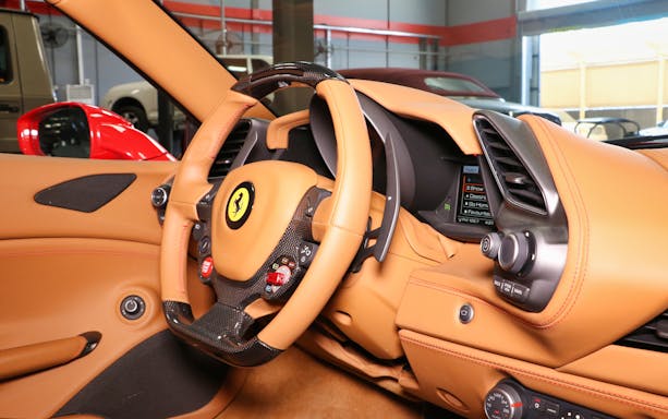 Luxury supercar interior with leather steering wheel and dashboard controls.
