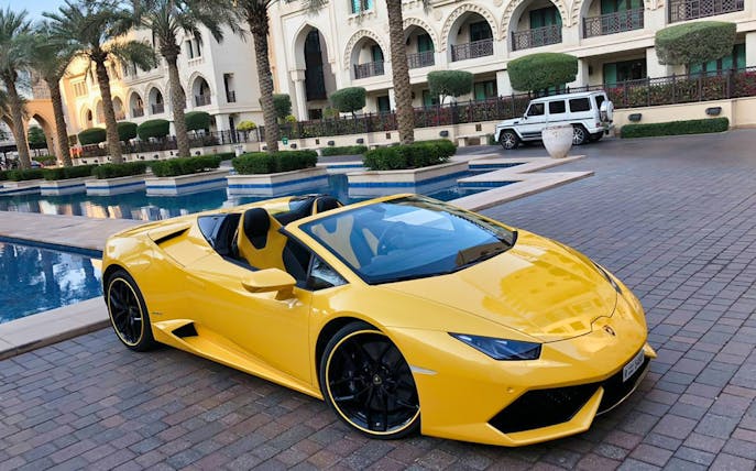 Yellow luxury supercar parked by a poolside at a resort.