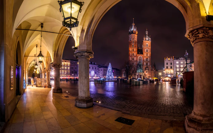 Krakow's Main Square at night with St. Mary's Basilica and festive lights.