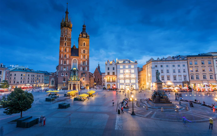 St. Mary's Basilica and Adam Mickiewicz Monument in Krakow's Main Square at dusk.