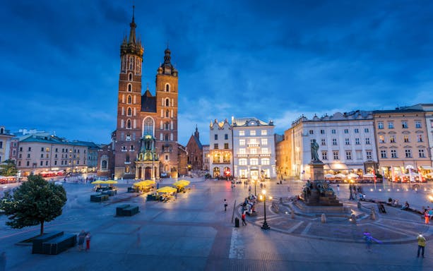 St. Mary's Basilica and Adam Mickiewicz Monument in Krakow's Main Square at dusk.