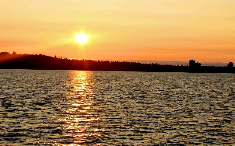 Sunset over water with city skyline, Five Star Sunset Dining & Jazz Cruise.