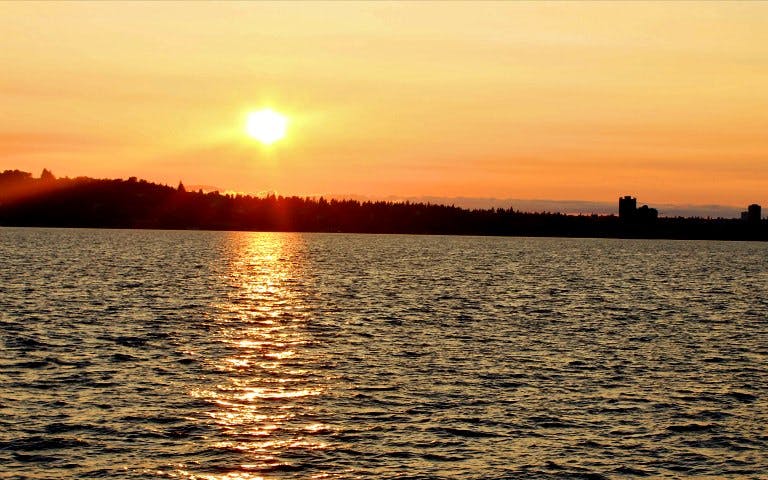 Sunset over water with city skyline, Five Star Sunset Dining & Jazz Cruise.