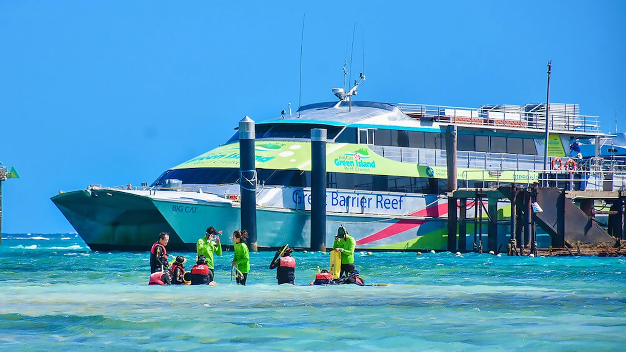 Catamaran docked at Green Island with tourists preparing for a reef cruise.