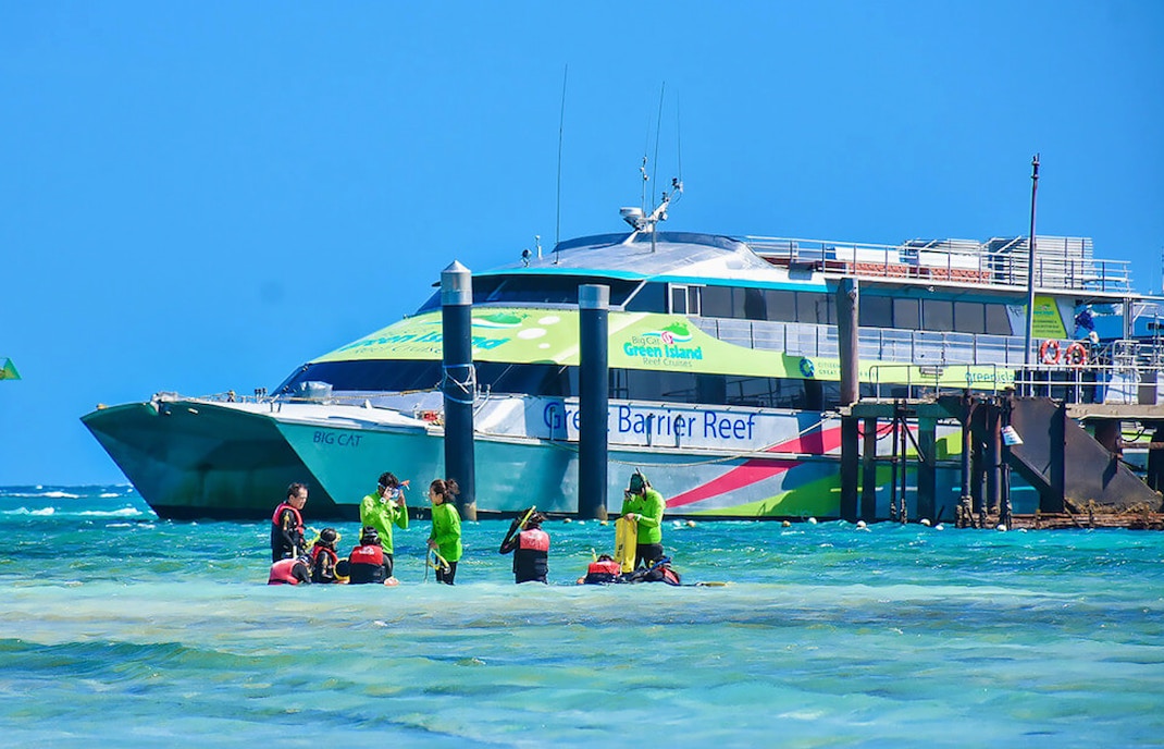 Catamaran docked at Green Island with tourists preparing for a reef cruise.