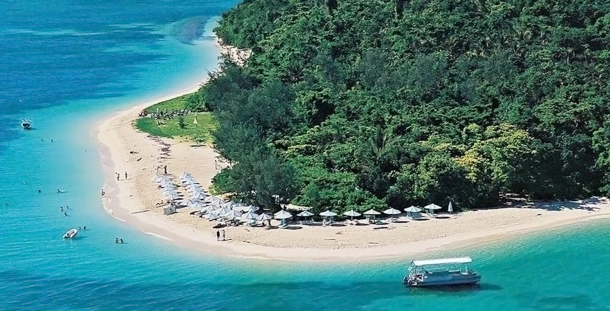 Catamaran near Green Island beach with semi-submarine in clear water.