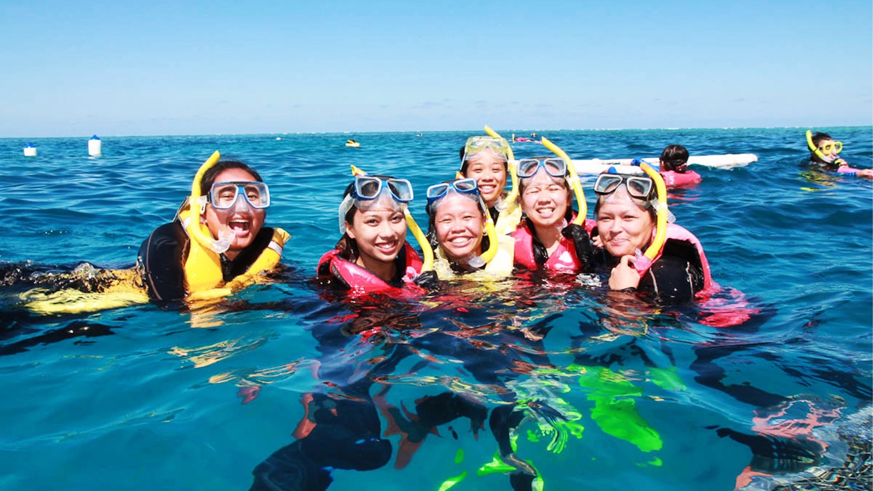 Snorkelers enjoying the Great Barrier Reef Adventure Cruise in clear blue waters.
