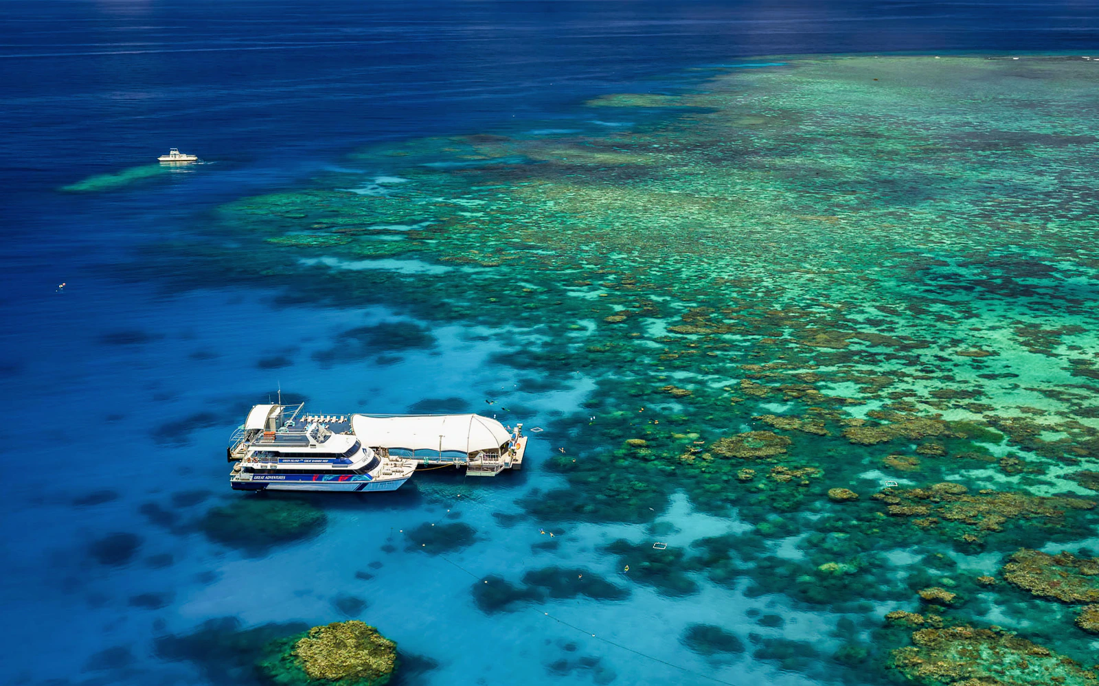 Cruise ship anchored near vibrant coral reefs at Great Barrier Reef, Australia.