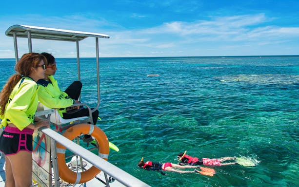 People snorkeling near a boat on the Great Barrier Reef Adventure Cruise.