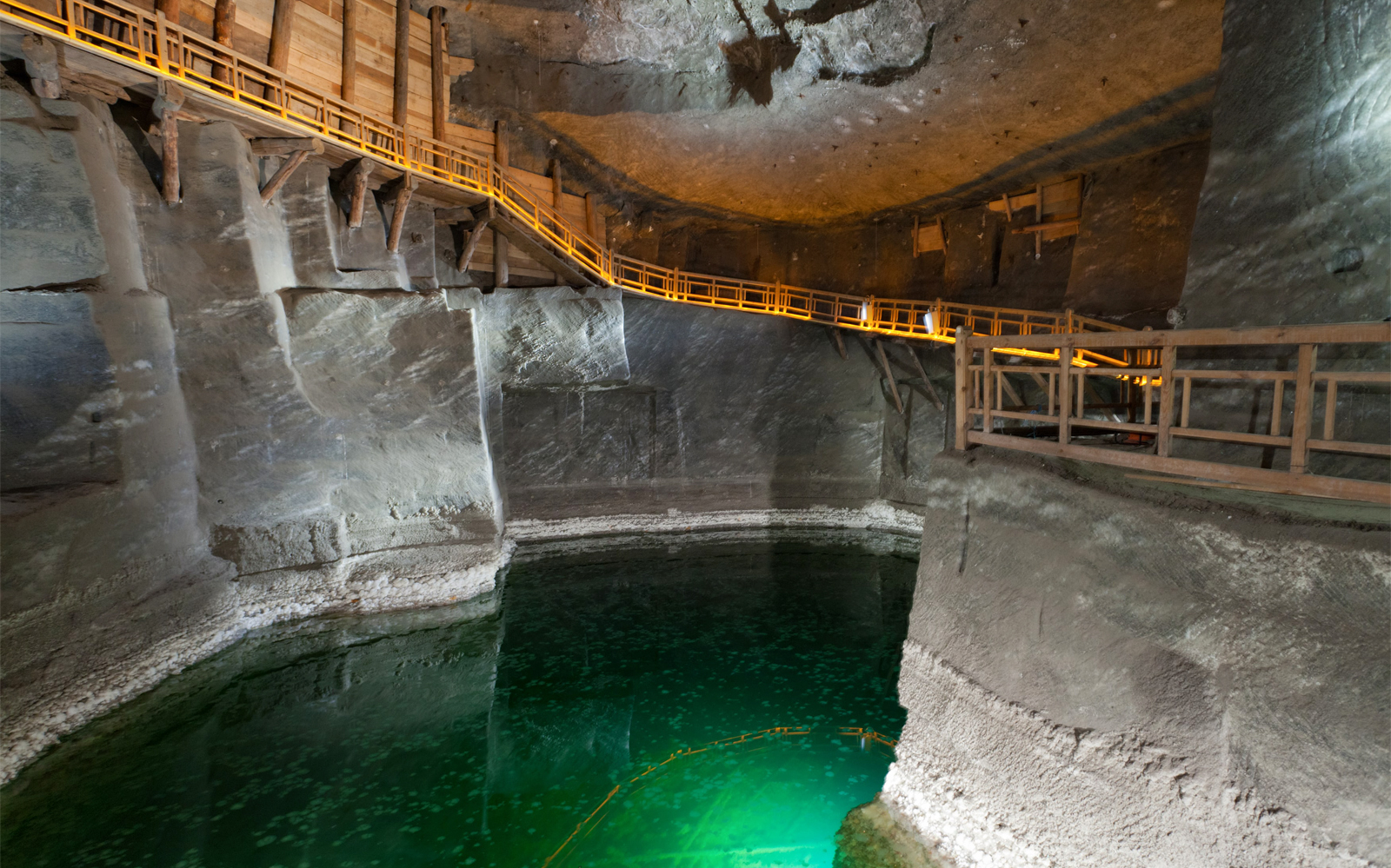 Wieliczka Salt Mine underground chamber with wooden walkway and green water.
