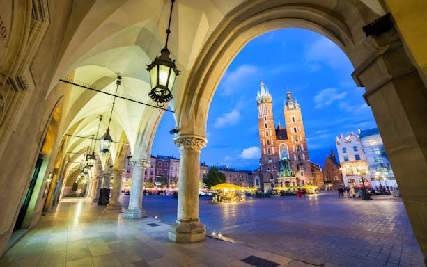 Arched walkway leading to St. Mary's Basilica on Krakow's Royal Route at dusk.