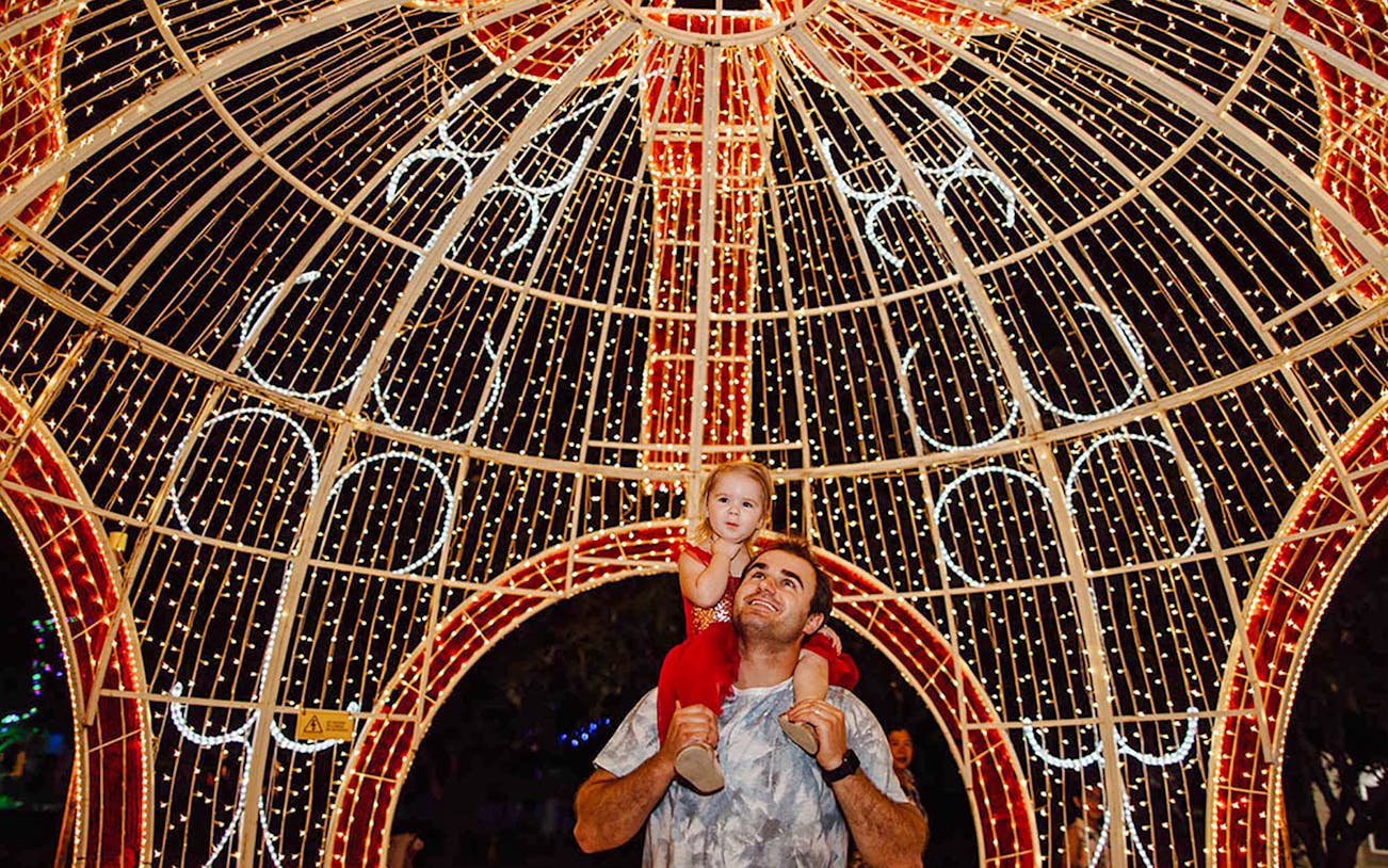 Father and child under illuminated arch at Hunter Valley Gardens Christmas Lights Spectacular.