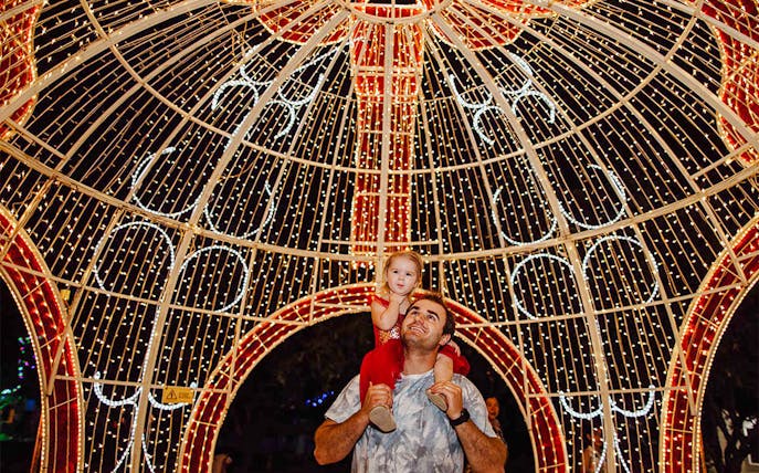 Father and child under illuminated arch at Hunter Valley Gardens Christmas Lights Spectacular.