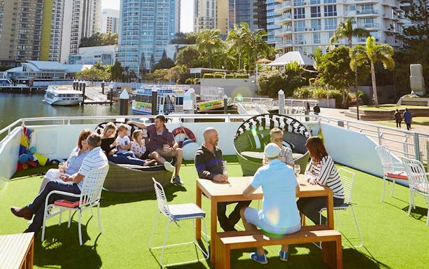 Group enjoying a Sea World sightseeing cruise on a sunny day with city skyline in the background.