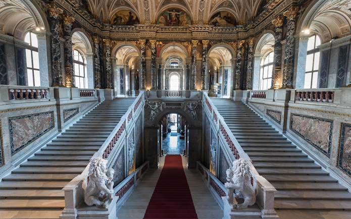 Staircase inside Kunsthistorisches Museum, Vienna, with ornate marble and sculptures.