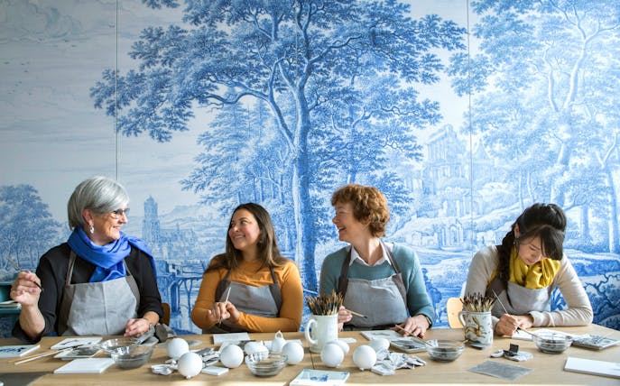 Visitors painting ceramics at Royal Delft Blue Factory workshop.