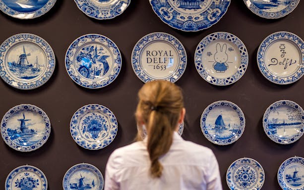 Visitor viewing Delft Blue plates at Royal Delft Blue Factory & Museum.