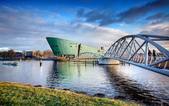 NEMO Science Museum in Amsterdam with pedestrian bridge over water.