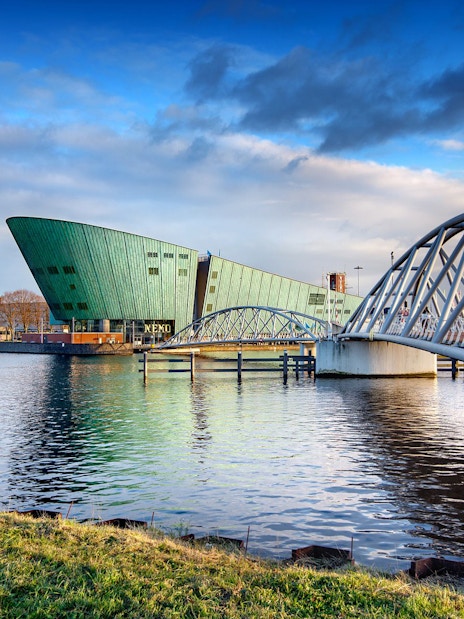 NEMO Science Museum in Amsterdam with pedestrian bridge over water.