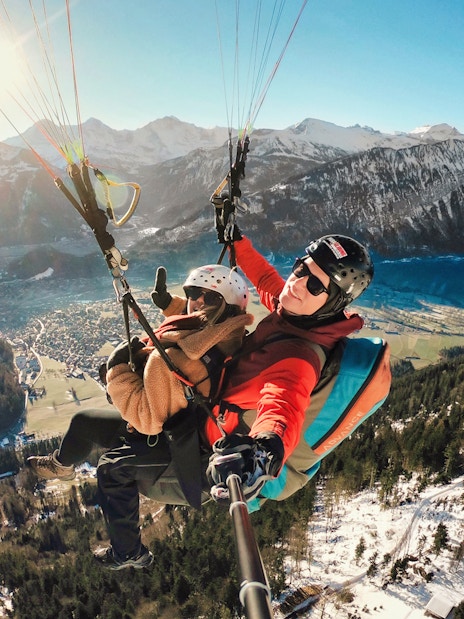 Paragliding over Interlaken with views of mountains and Lake Thun.