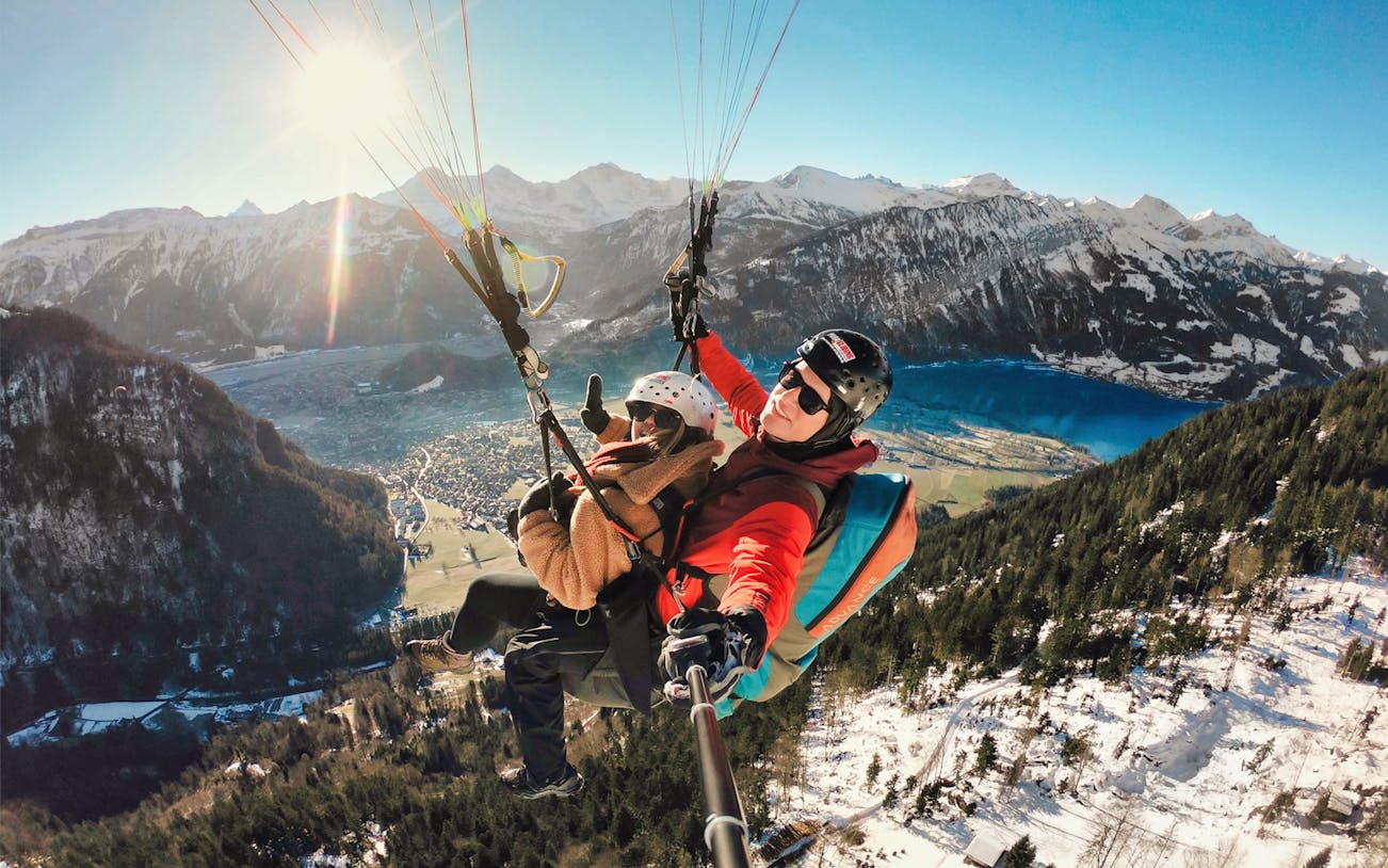 Paragliding over Interlaken with views of mountains and Lake Thun.