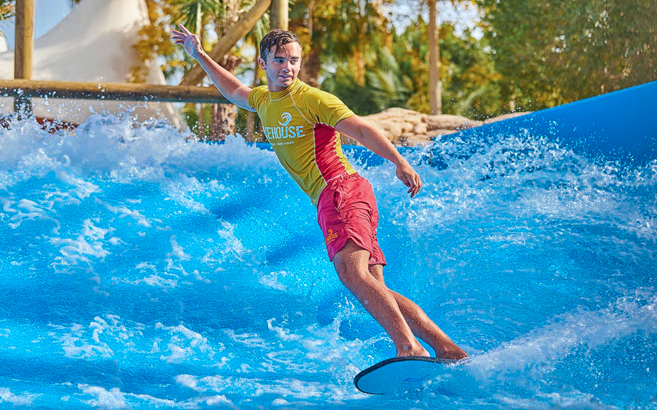 Surfer riding artificial wave at Aquaventure water park, part of IMG Worlds combo tour.