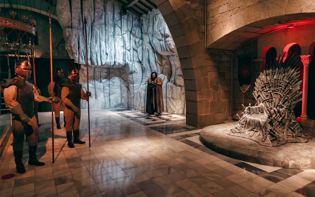 Wax figures in medieval attire near a throne at Wax Museum Barcelona.