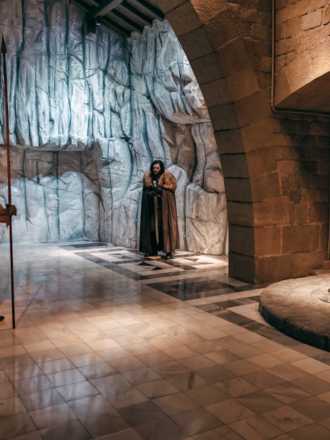 Wax figures in medieval attire near a throne at Wax Museum Barcelona.