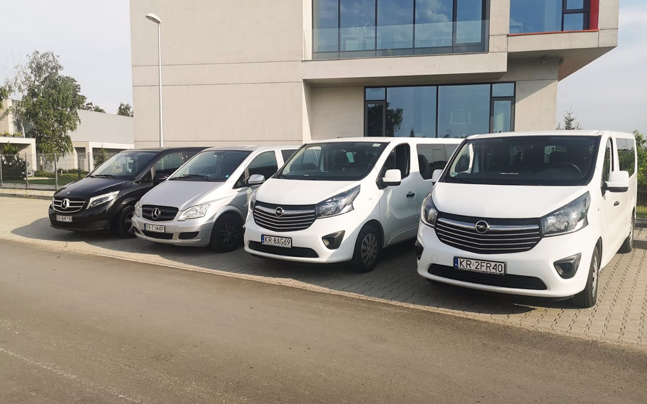 Vans for Krakow Balice Airport transfers parked outside a modern building.