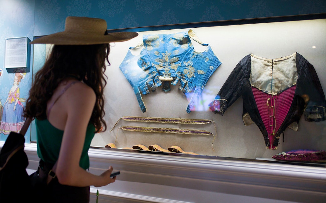 Visitor viewing historical silk garments at Silk Museum Valencia exhibit.