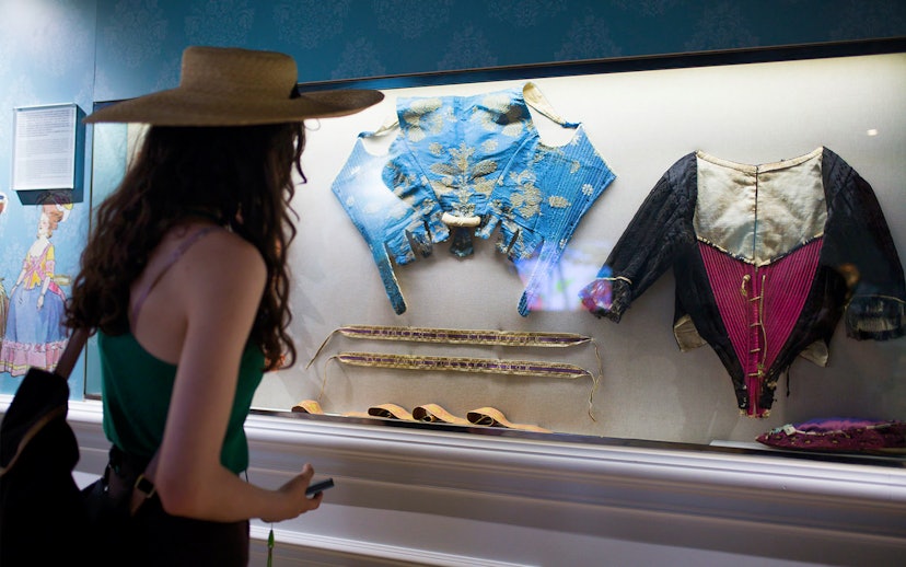 Visitor viewing historical silk garments at Silk Museum Valencia exhibit.