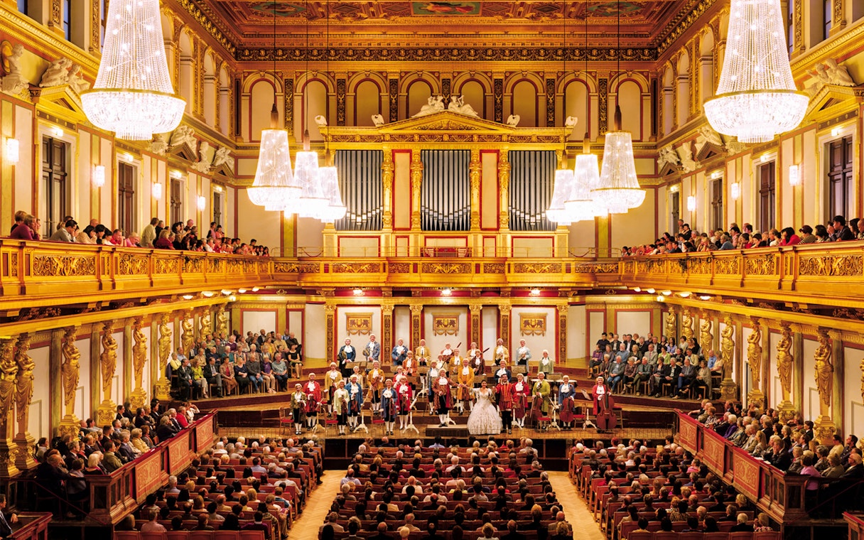 Mozart Orchestra performing at Wiener Musikverein, Vienna, with audience in ornate concert hall.
