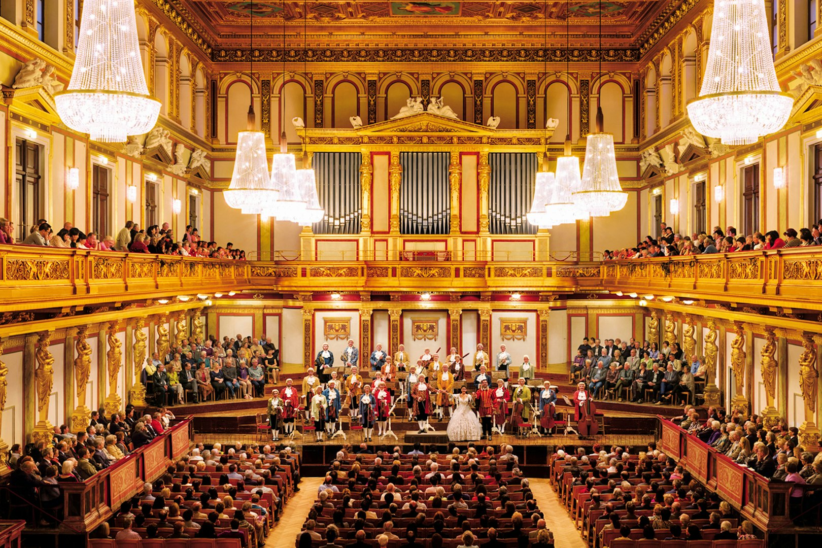 Mozart Orchestra performing at Wiener Musikverein, Vienna, with audience in ornate concert hall.
