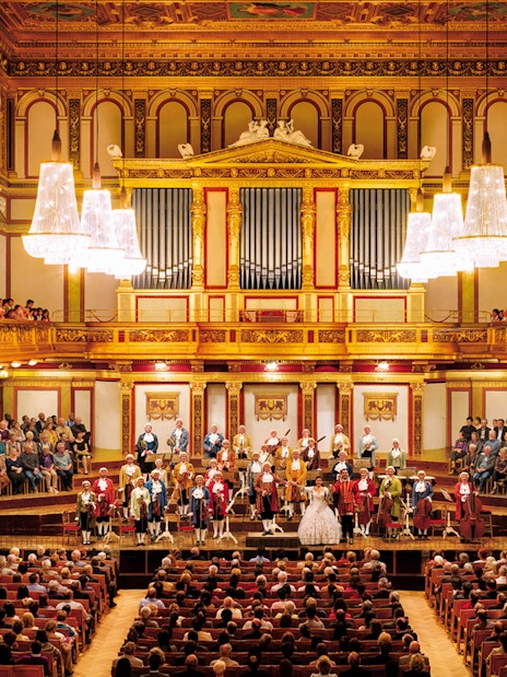 Mozart Orchestra performing at Wiener Musikverein, Vienna, with audience in ornate concert hall.