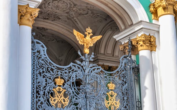 Hermitage Museum ornate gate with golden double-headed eagle emblem.