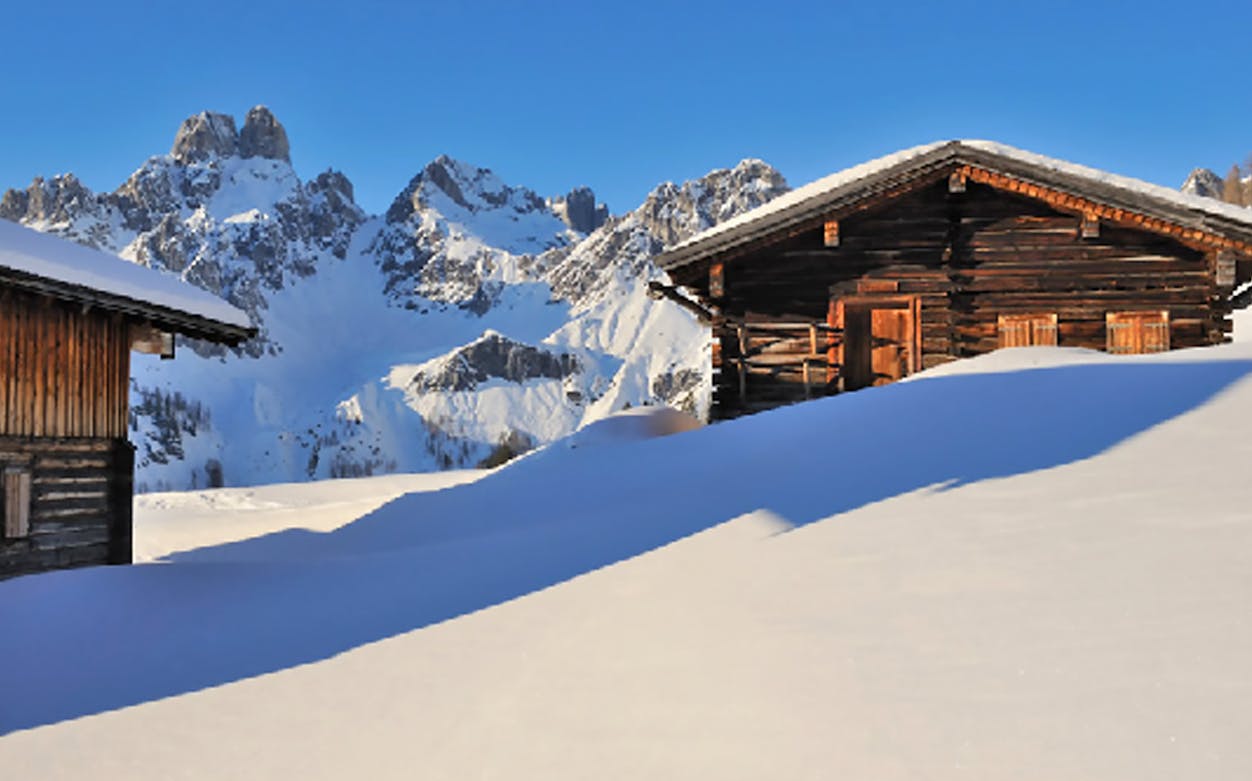 Wooden cabins in snowy landscape with mountains in Ski Amade, Austria.